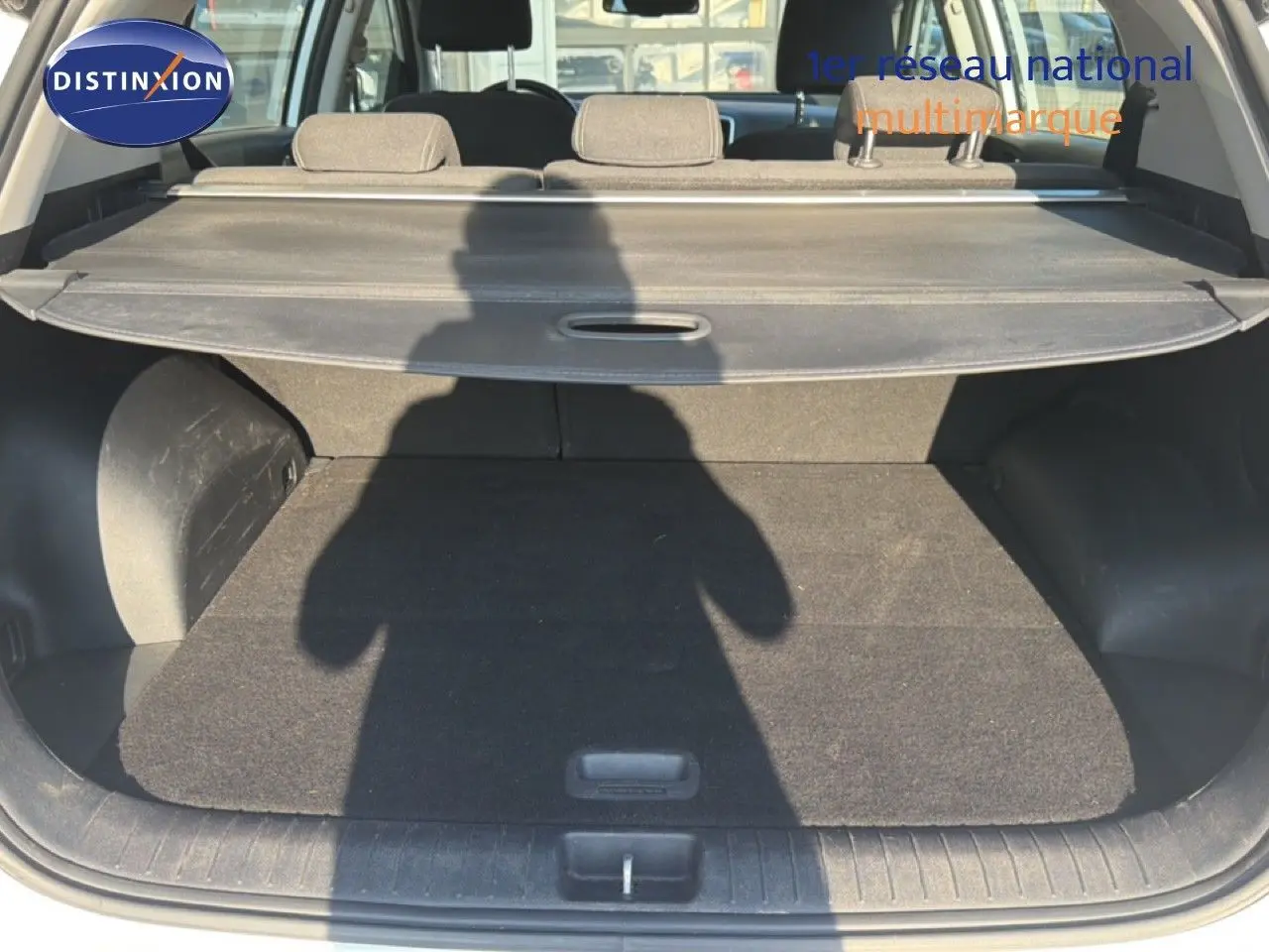 Coffre ouvert d'un KIA Sportage blanc nacré, vue arrière montrant la plage arrière et l'espace de chargement.