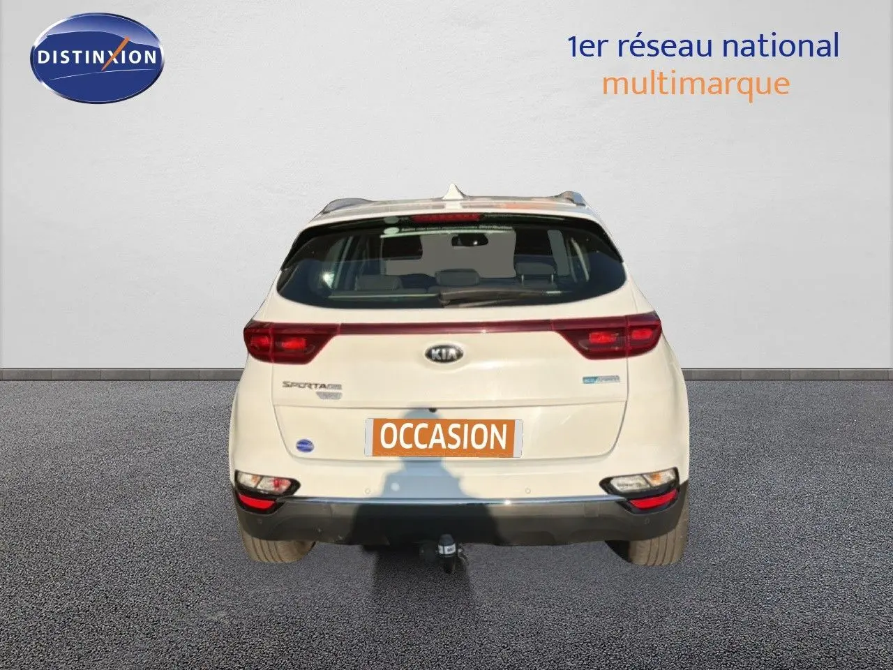 Vue arrière d'un Kia Sportage blanc nacré métal 2021 avec attelage et feux LED visibles.