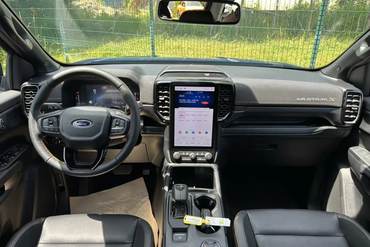 Vue intérieure avant du Ford Ranger Wildtrak X 2026 avec tableau de bord noir, écran tactile vertical et volant cuir multifonctions.