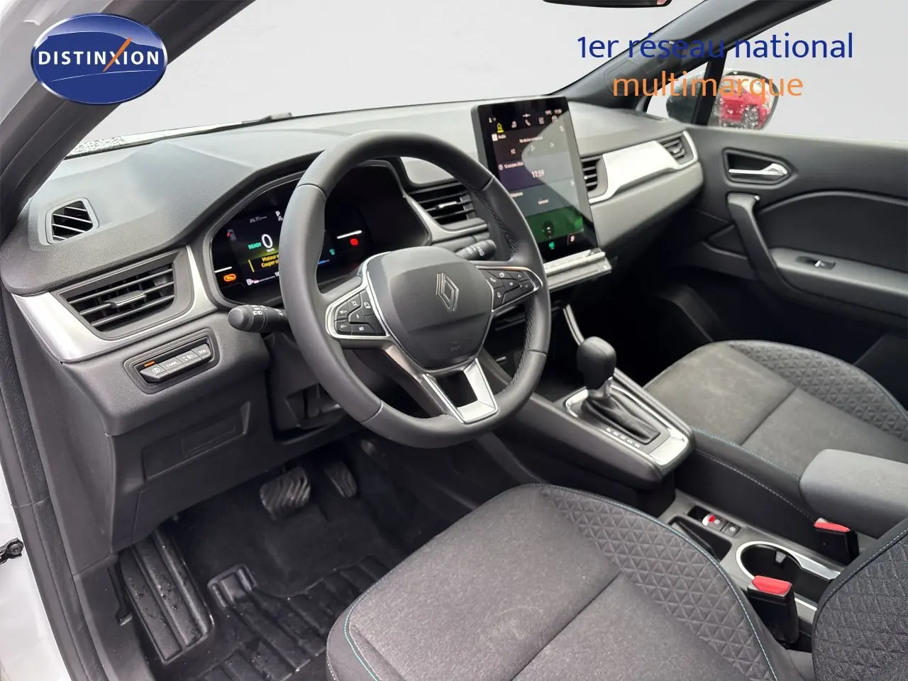 Vue intérieure côté conducteur du Renault Symbioz blanc nacré, mettant en valeur le volant multifonction et la console centrale avec boîte auto.