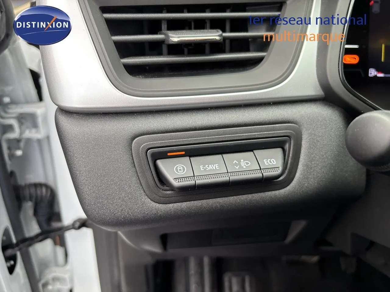 Gros plan sur les commandes E-SAVE et ECO du tableau de bord d’un Renault Symbioz blanc nacré, côté gauche.