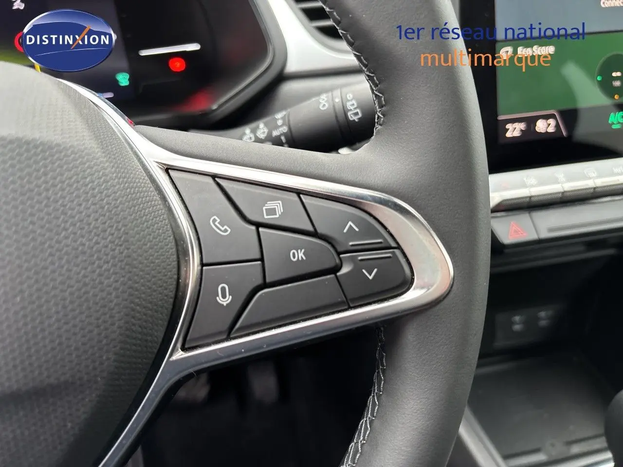 Gros plan sur les commandes au volant à droite du Renault Symbioz blanc nacré, avec tableau de bord numérique en arrière-plan.