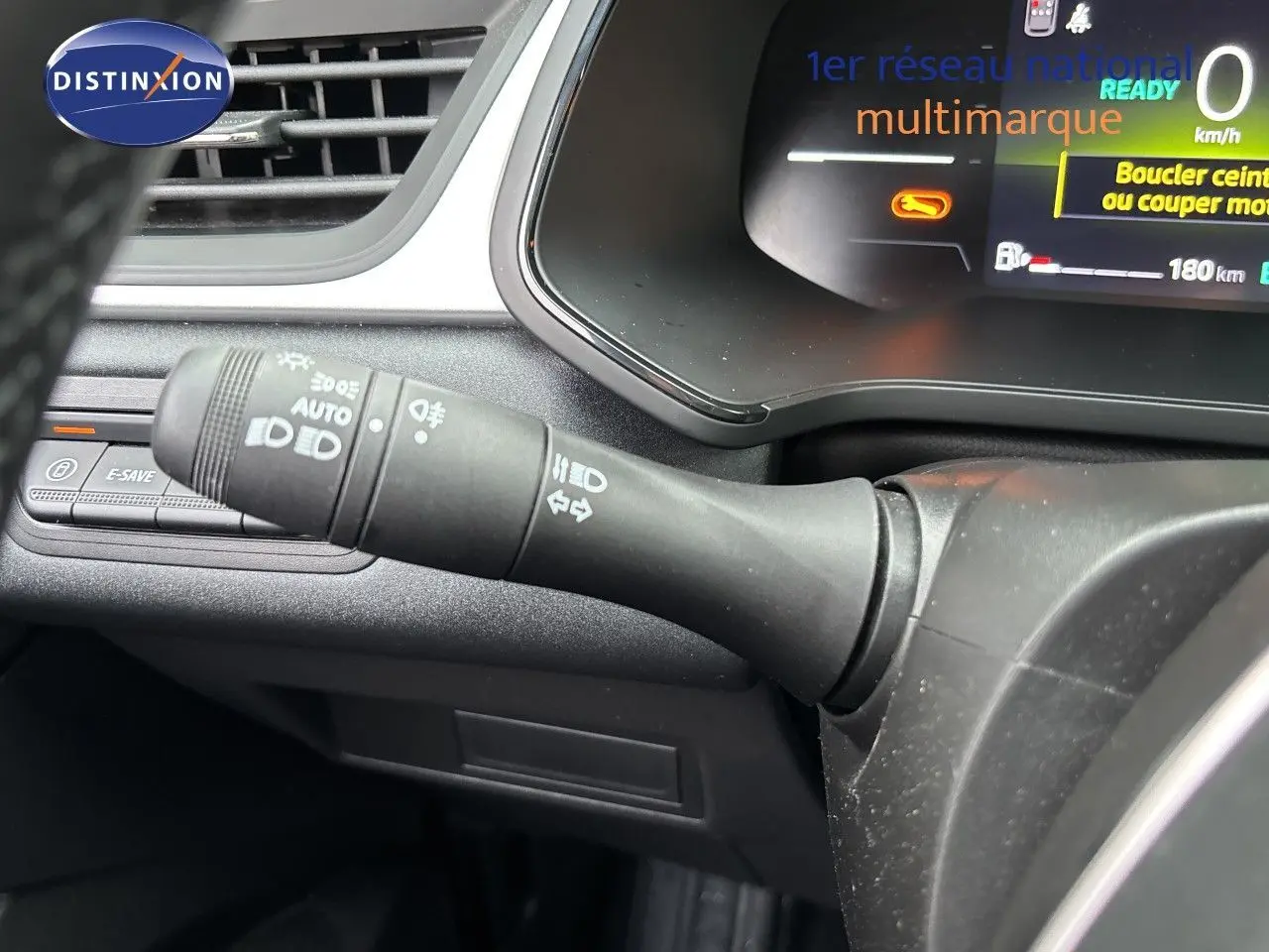 Gros plan sur la commande des phares et clignotants à gauche du volant du Renault Symbioz blanc nacré, tableau de bord numérique visible.