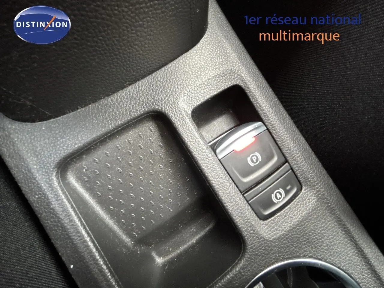Gros plan sur la console centrale noire avec bouton frein à main électronique et fonction auto hold, intérieur tissu noir.