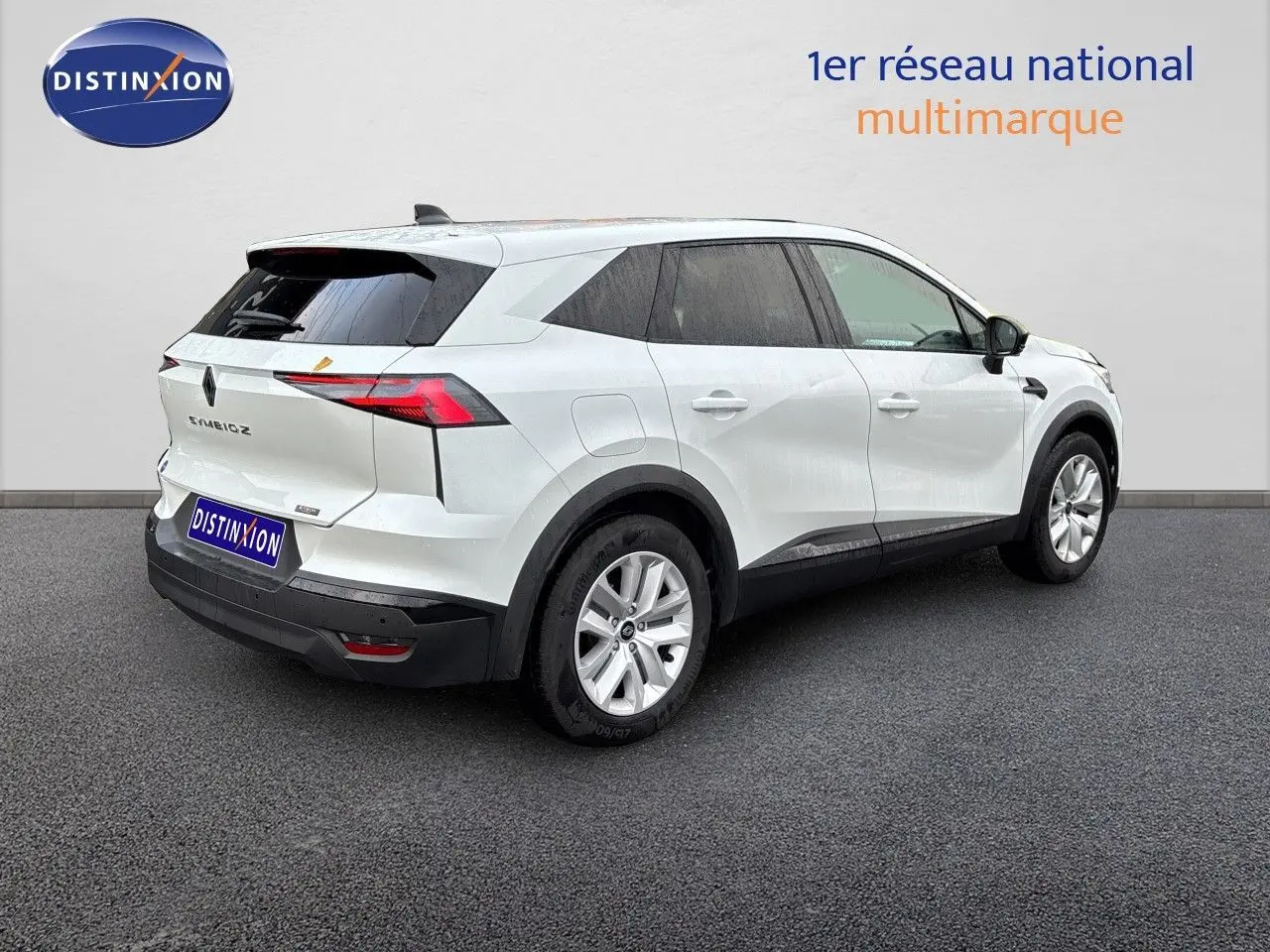 Vue 3/4 arrière droite d'un Renault Symbioz blanc nacré avec feux LED et jantes alliage sur fond neutre.