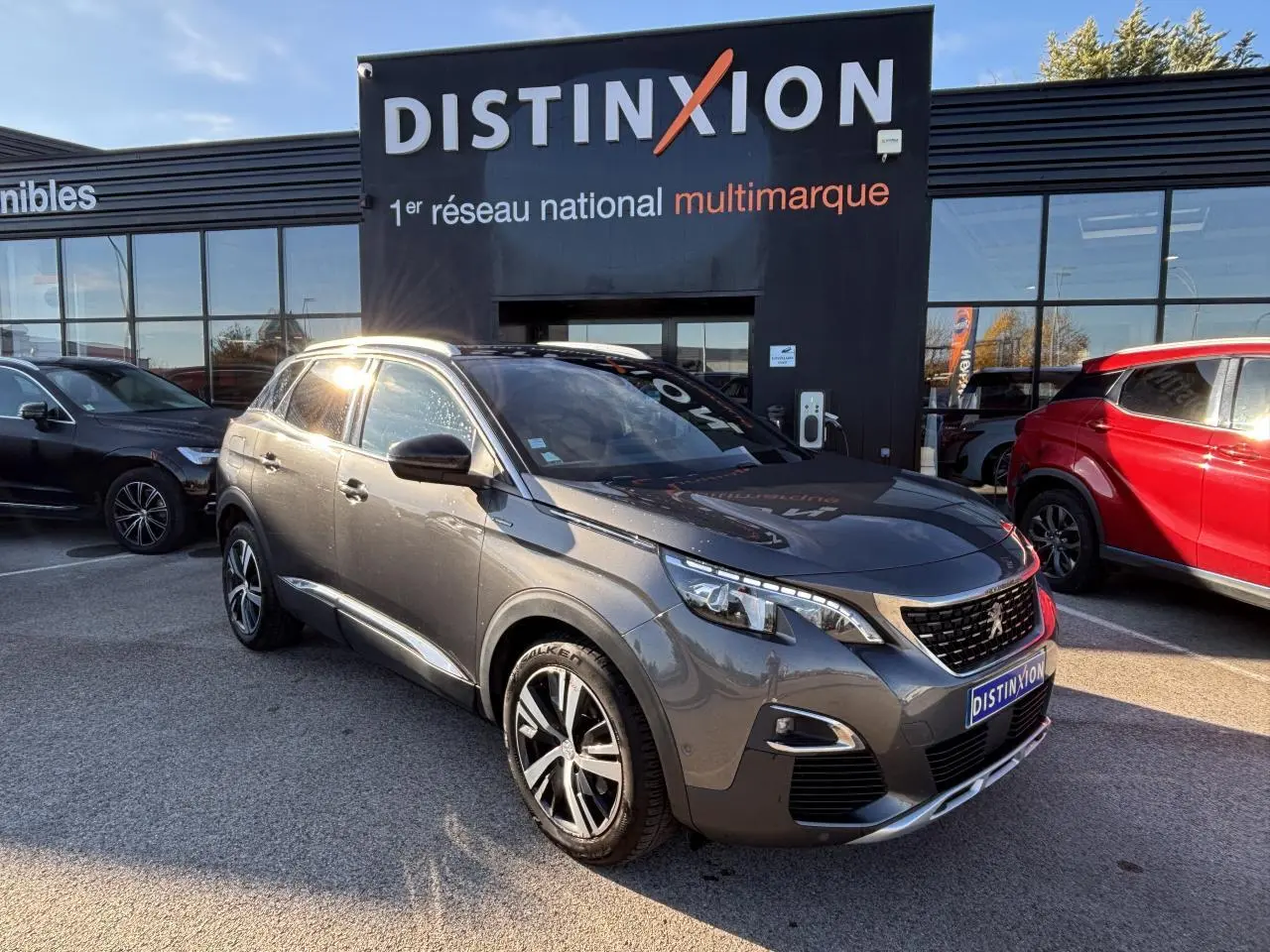 Peugeot 3008 gris métal en 3/4 avant droit, avec jantes alliage et calandre distinctive GT Line devant un showroom Distinxion.