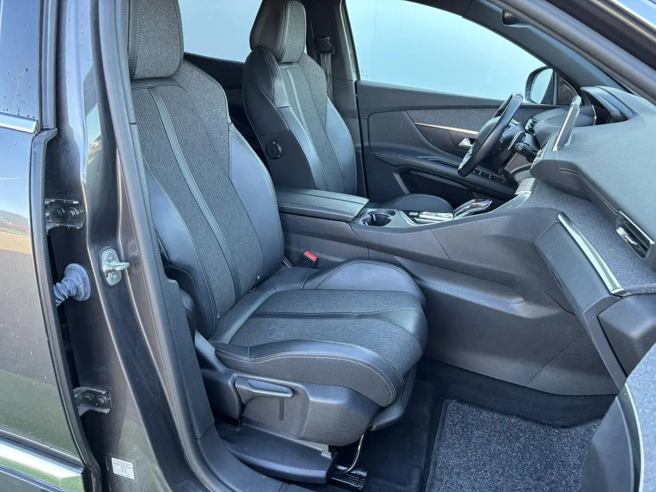 Intérieur côté conducteur du Peugeot 3008 gris métal 2020, sièges en tissu et cuir, tableau de bord moderne visible.
