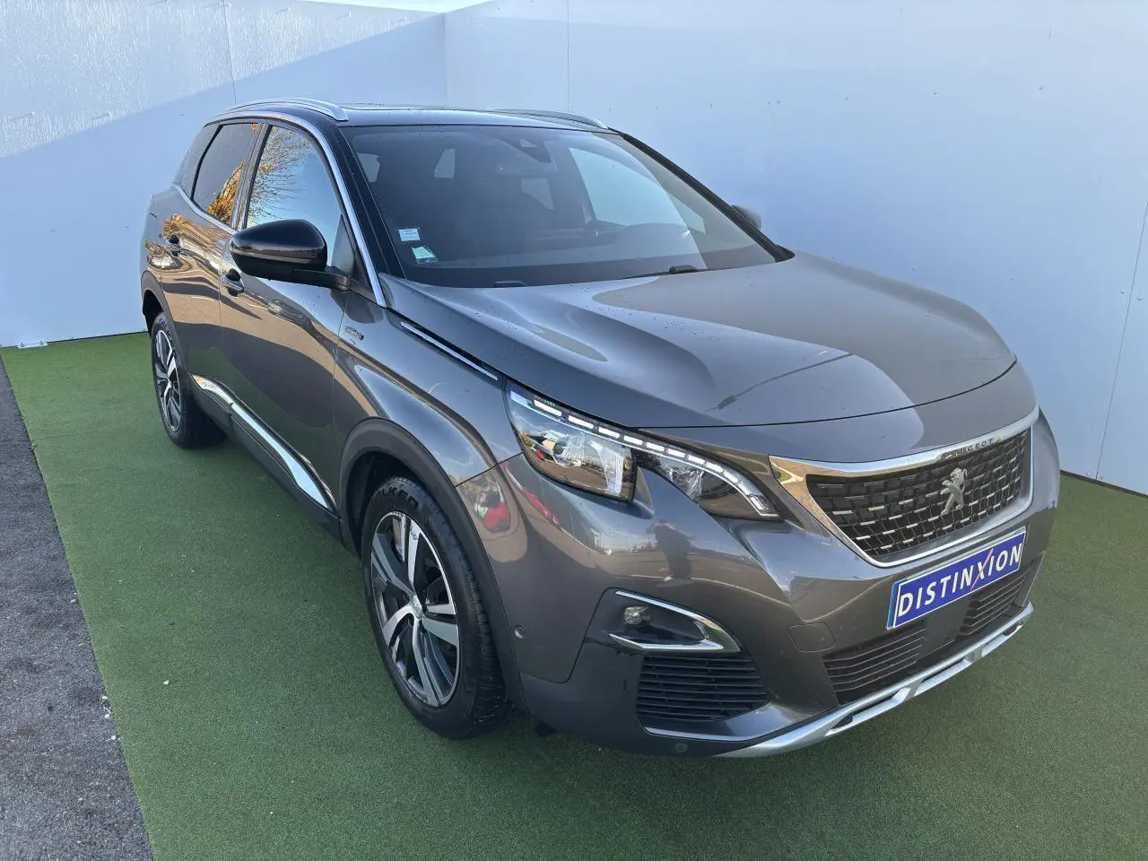 Peugeot 3008 gris métal vue 3/4 avant droit, avec calandre distinctive et jantes alliage modernes.