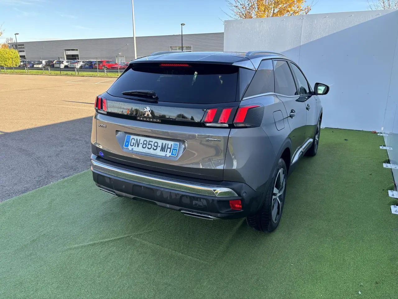 Vue 3/4 arrière droite d'un Peugeot 3008 gris métal 2020 avec feux arrière à griffes et toit noir brillant.