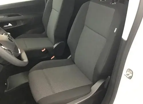 Vue intérieure côté conducteur du Peugeot Rifter blanc banquise 2025, sièges avant en tissu gris et noir.