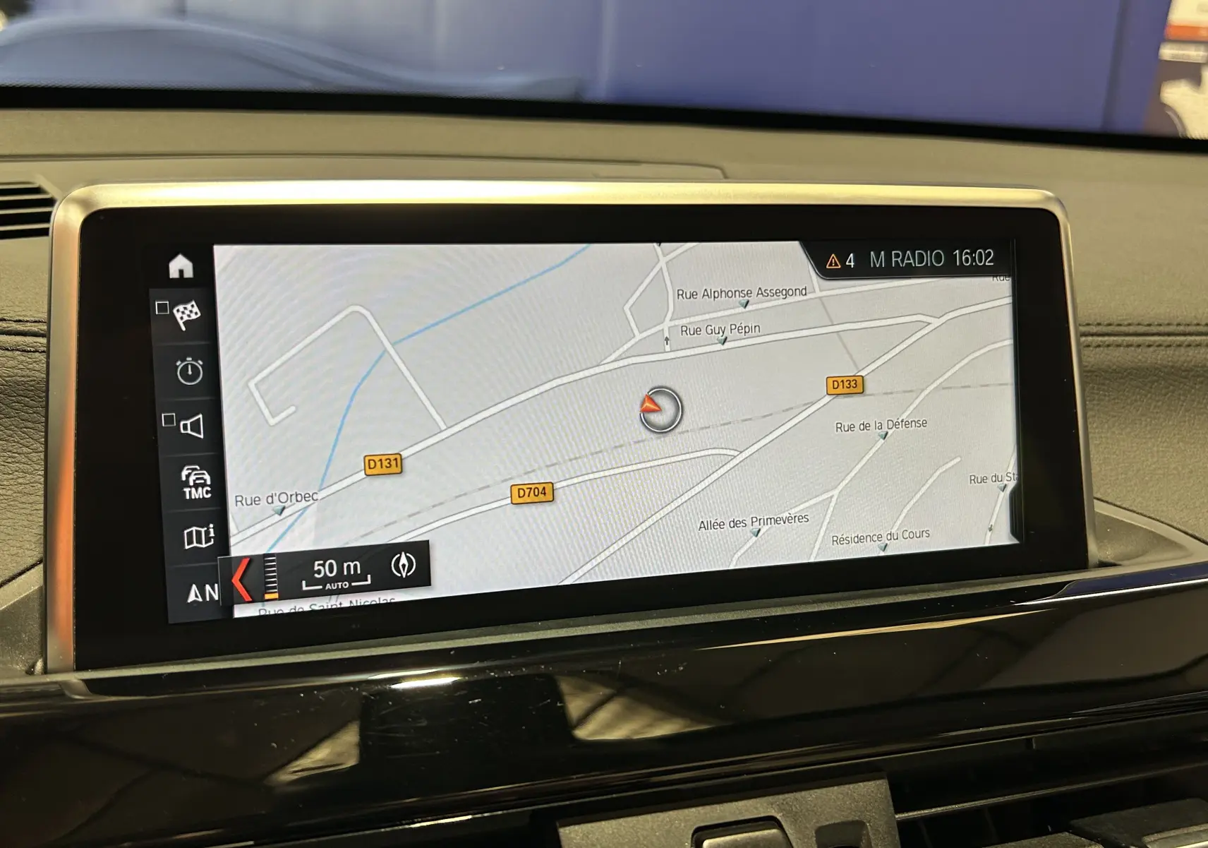 Écran central du tableau de bord BMW X1 noir 2019 affichant la navigation GPS avec carte détaillée des rues environnantes.
