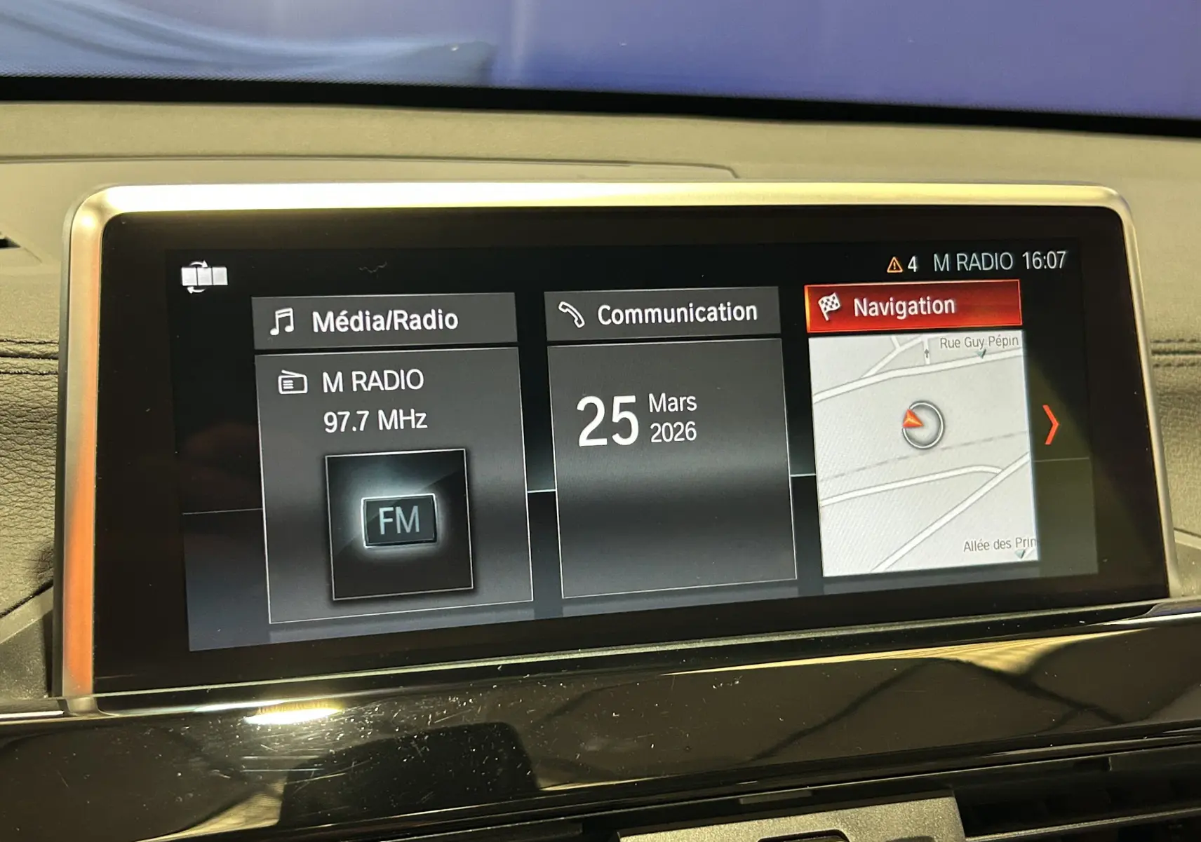 Écran central de navigation et radio du BMW X1 noir, affichant la date et la carte GPS en intérieur.