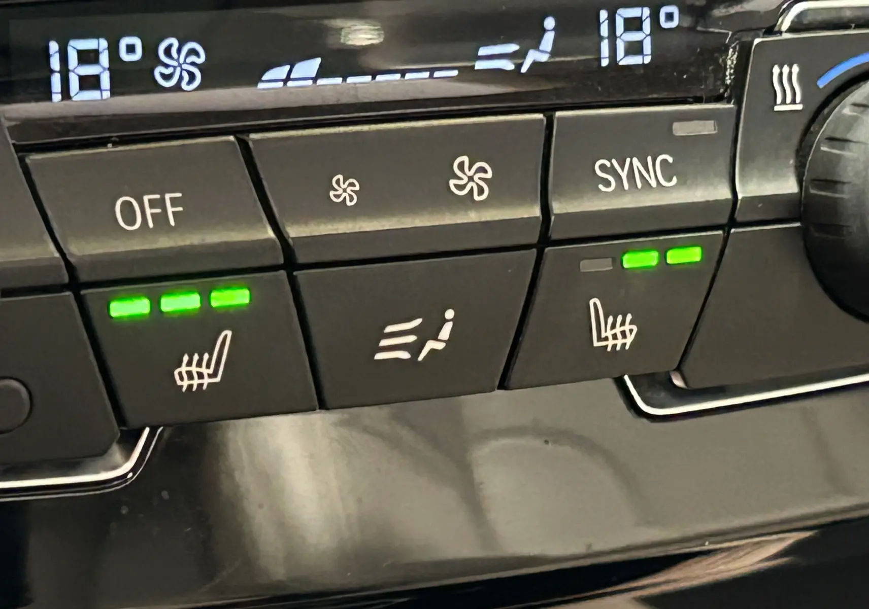 Détail du tableau de bord BMW X1 noir 2019 montrant les commandes de climatisation et sièges chauffants activés.