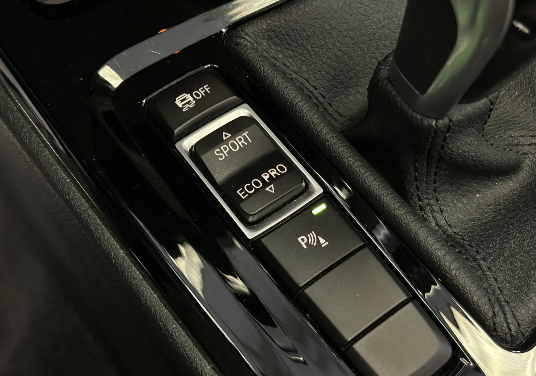 Gros plan sur la console centrale noire du BMW X1 2019 montrant les boutons de mode de conduite Sport et Eco Pro.