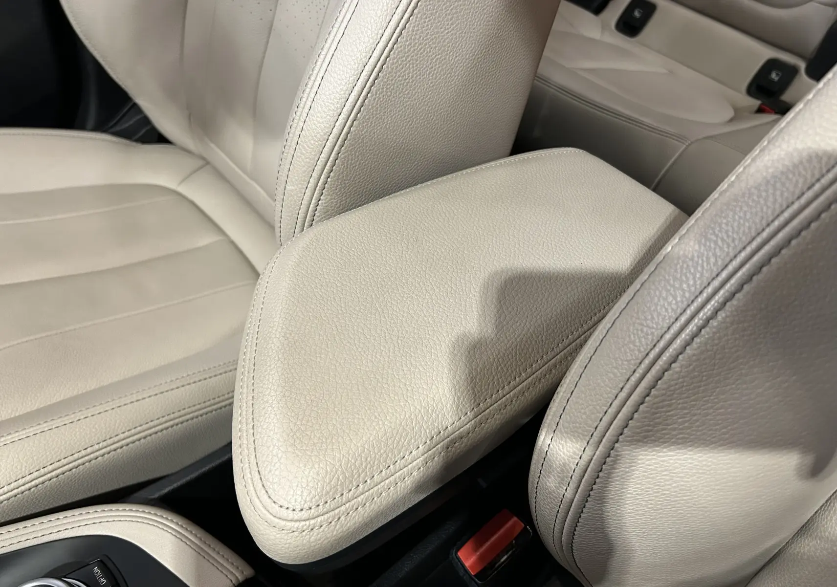 Gros plan sur l'accoudoir central en cuir beige clair à l'intérieur du BMW X1 sDrive18iA 2019.