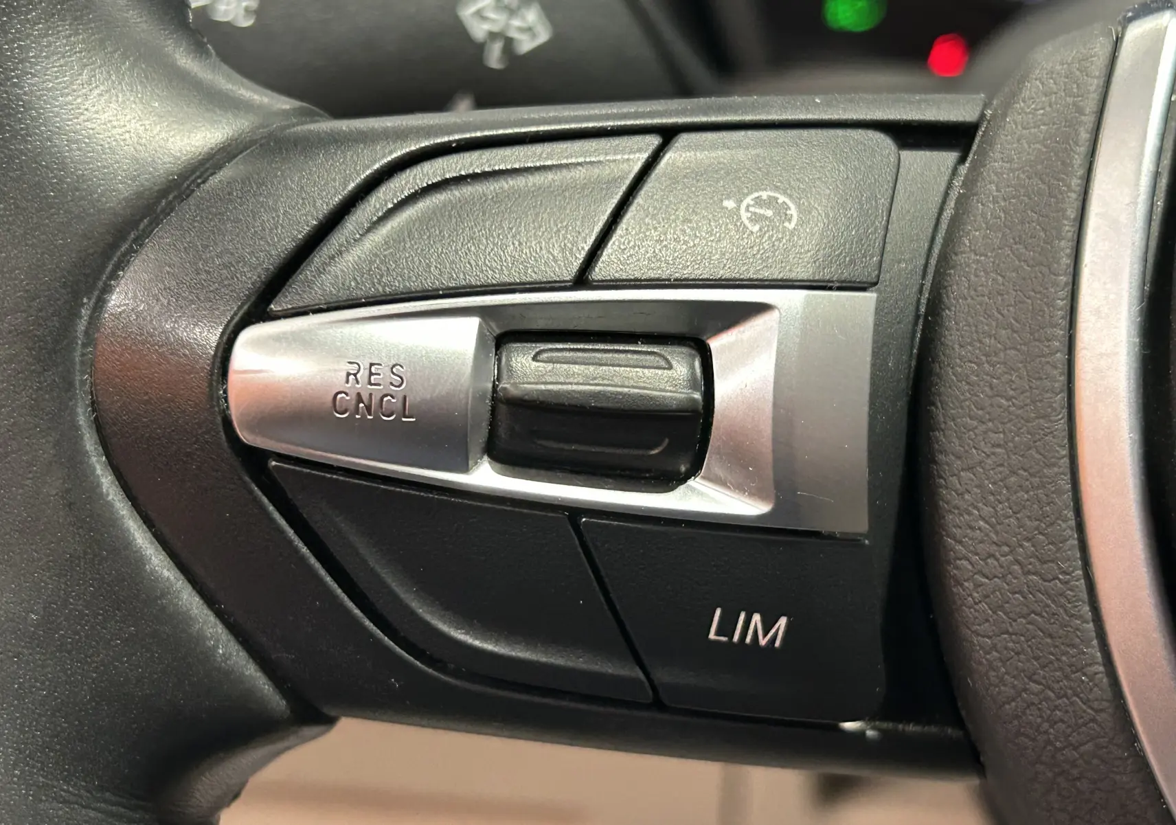 Gros plan sur les commandes de régulateur de vitesse au volant noir du BMW X1 sDrive18iA 2019.