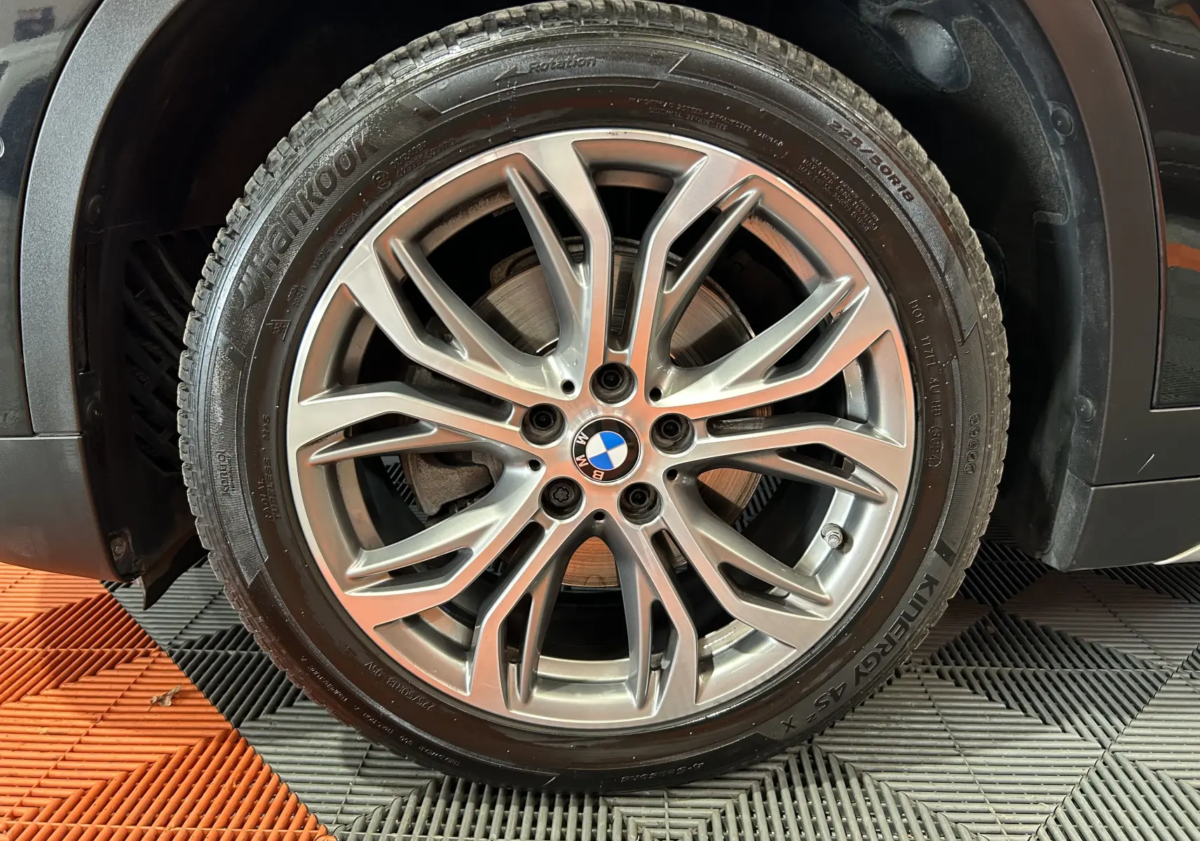 Gros plan sur la jante alliage argentée BMW montée sur le côté droit d'un BMW X1 noir.