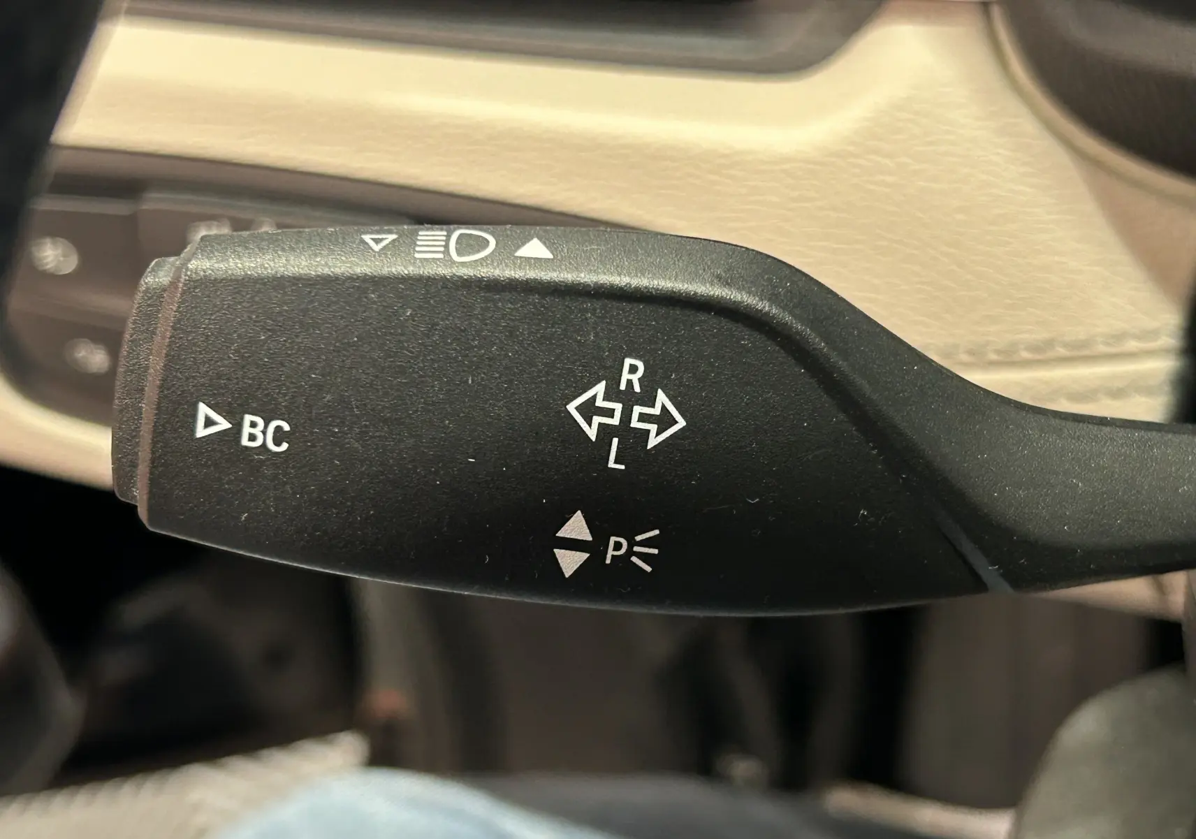 Gros plan sur la manette de clignotant noire à l'intérieur du BMW X1, avec commandes BC et indicateurs lumineux.