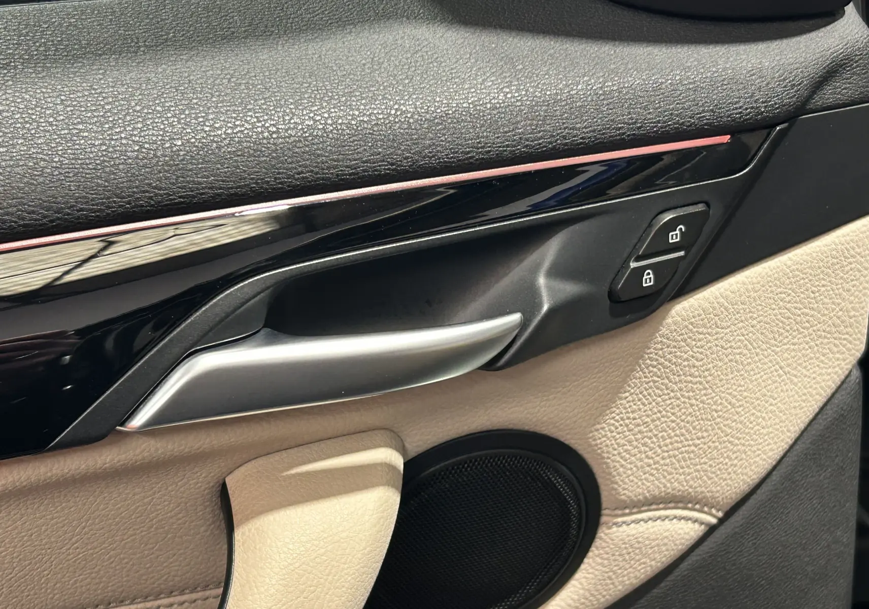 Détail de la poignée intérieure côté gauche de la porte beige et noire d’un BMW X1 2019 avec commandes de verrouillage.