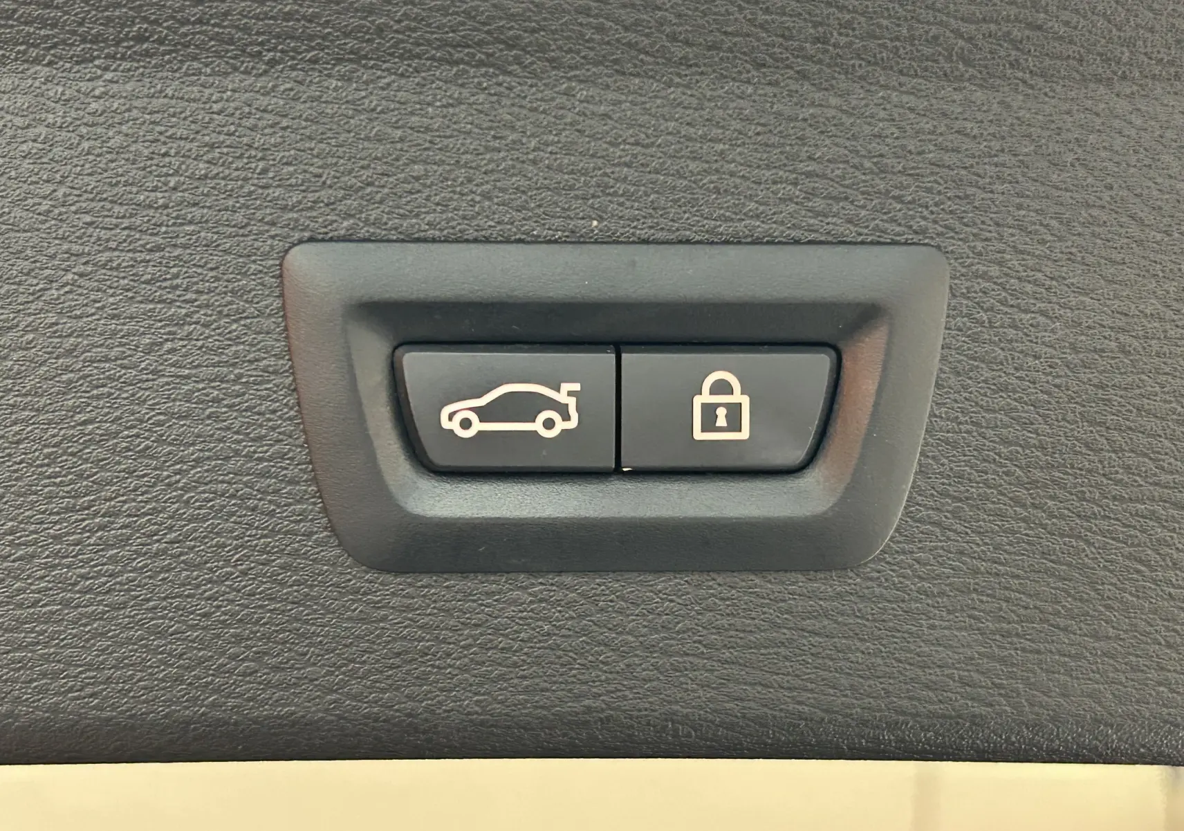 Gros plan sur les boutons d'ouverture du hayon électrique et de verrouillage dans un BMW X1 noir, version xLine.