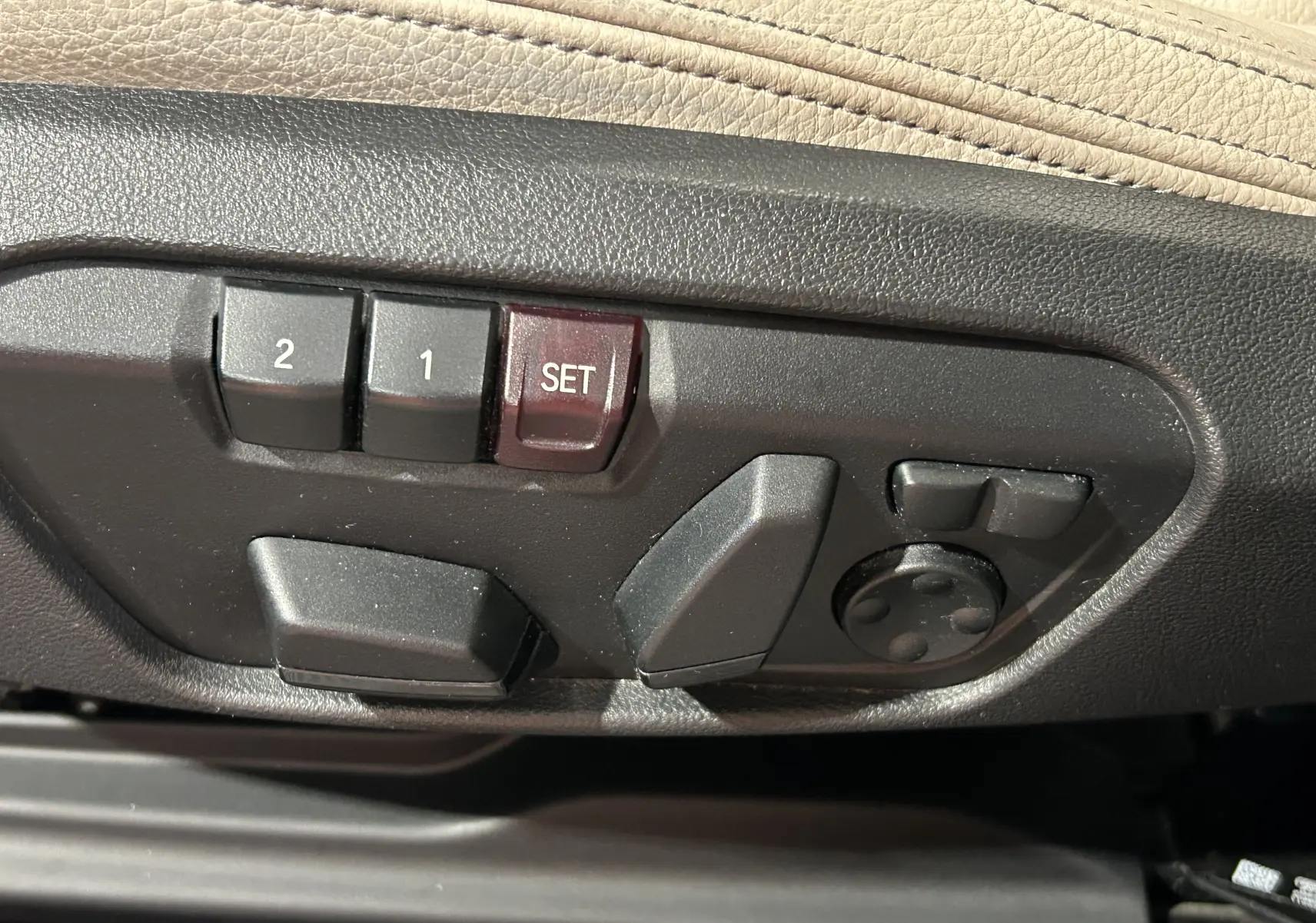 Gros plan sur les commandes de réglage électrique des sièges en cuir beige d'un BMW X1 noir 2019.