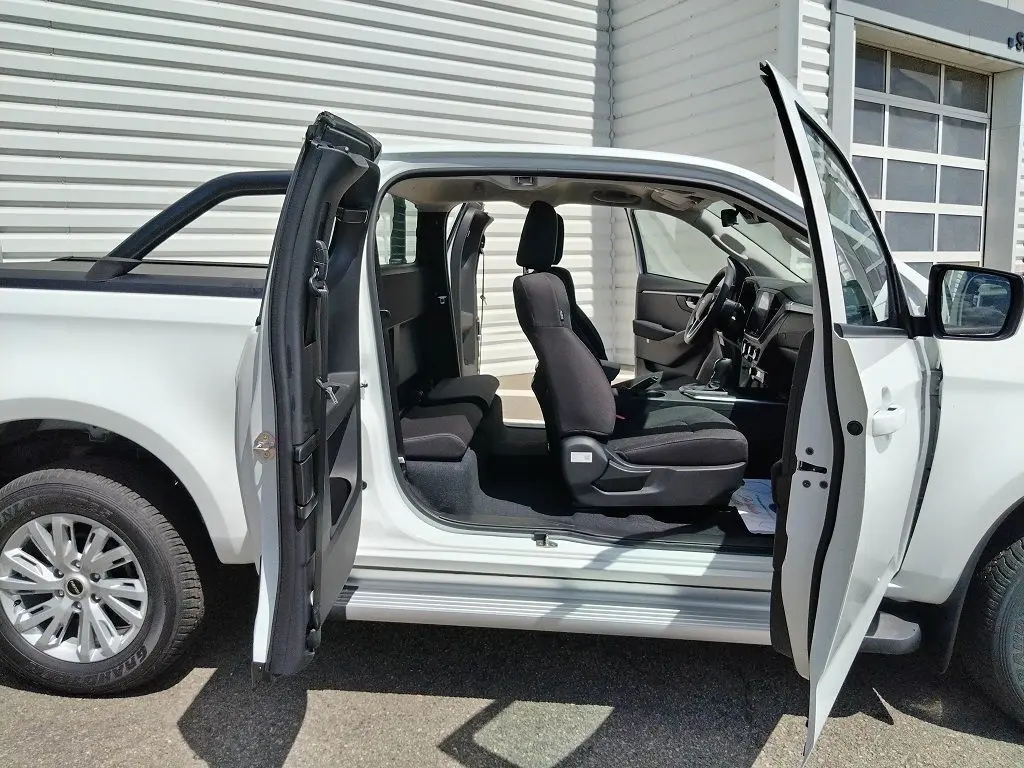 Vue latérale gauche d'un Isuzu D-MAX blanc 2026 avec portes ouvertes, arceau et bac de benne visible.