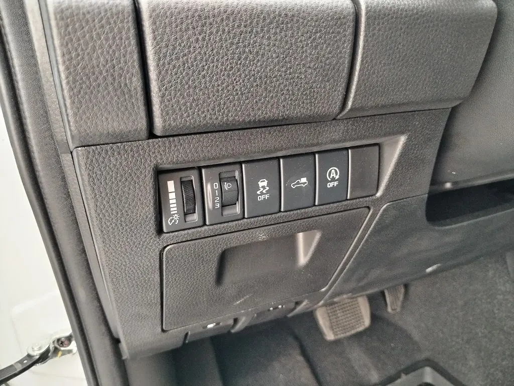 Vue rapprochée des commandes de réglage et d'assistance situées à gauche du volant dans un Isuzu D-MAX blanc 2026.