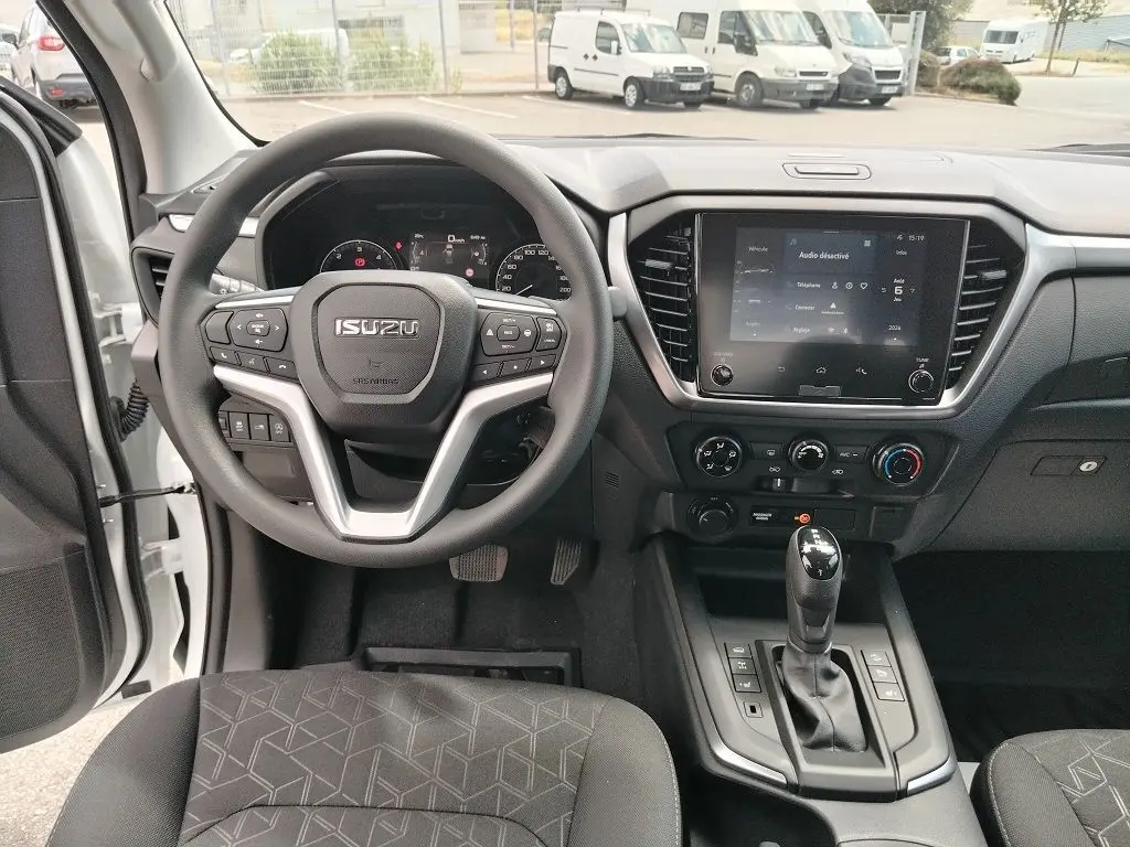 Vue intérieure avant de l'Isuzu D-MAX 2026, tableau de bord avec volant multifonction et écran tactile central.