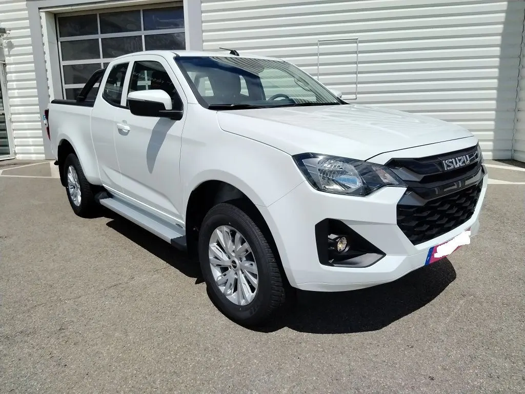 Isuzu D-MAX blanc en 3/4 avant droit, avec arceau et volet couvre benne roulant visible sur un parking extérieur.