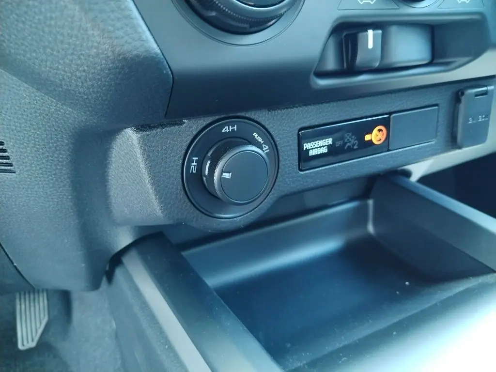 Gros plan intérieur sur le tableau de bord noir de l'Isuzu D-MAX 2026, avec commande de traction 4x4 et témoin airbag passager.