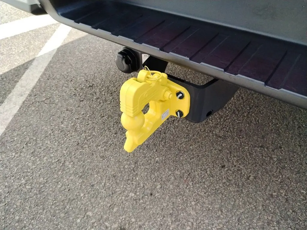 Gros plan sur le crochet d'attelage jaune fixé à l'arrière d'un pick-up Isuzu D-MAX blanc.