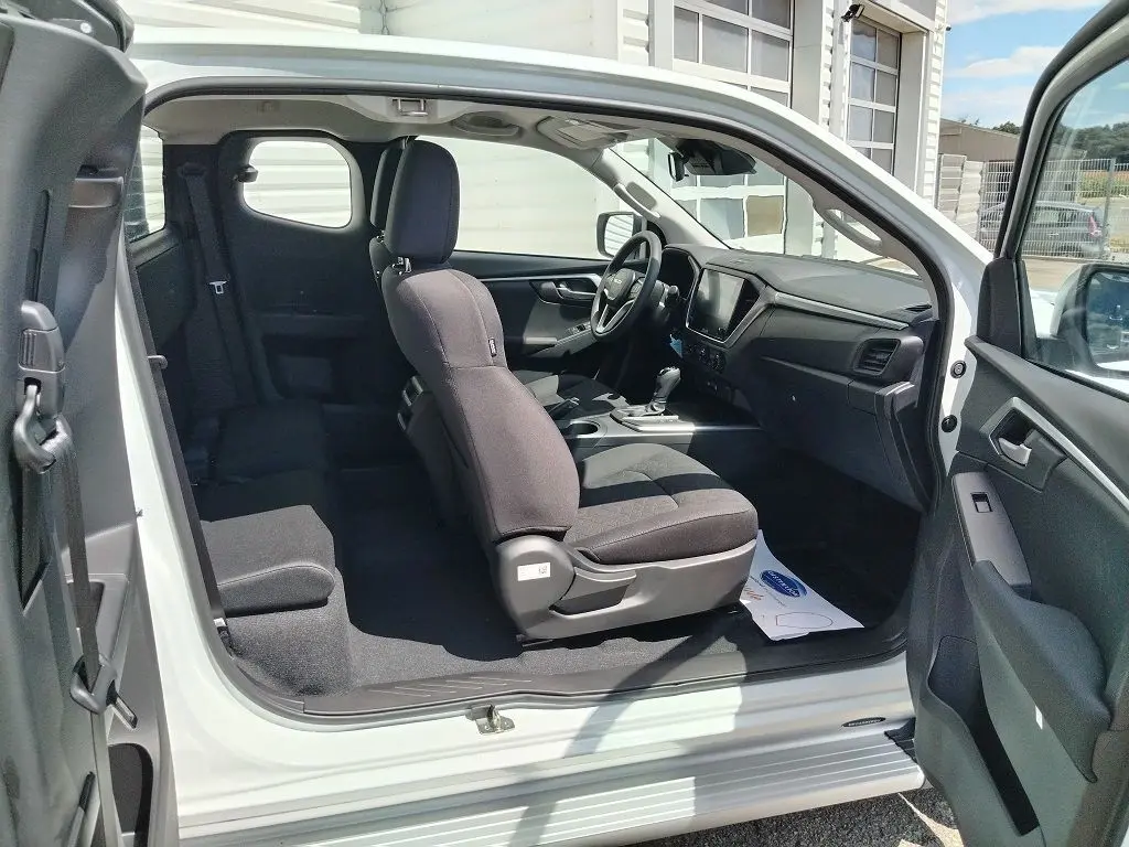 Intérieur du pick-up Isuzu D-MAX blanc vu côté gauche avec sièges noirs et tableau de bord moderne.