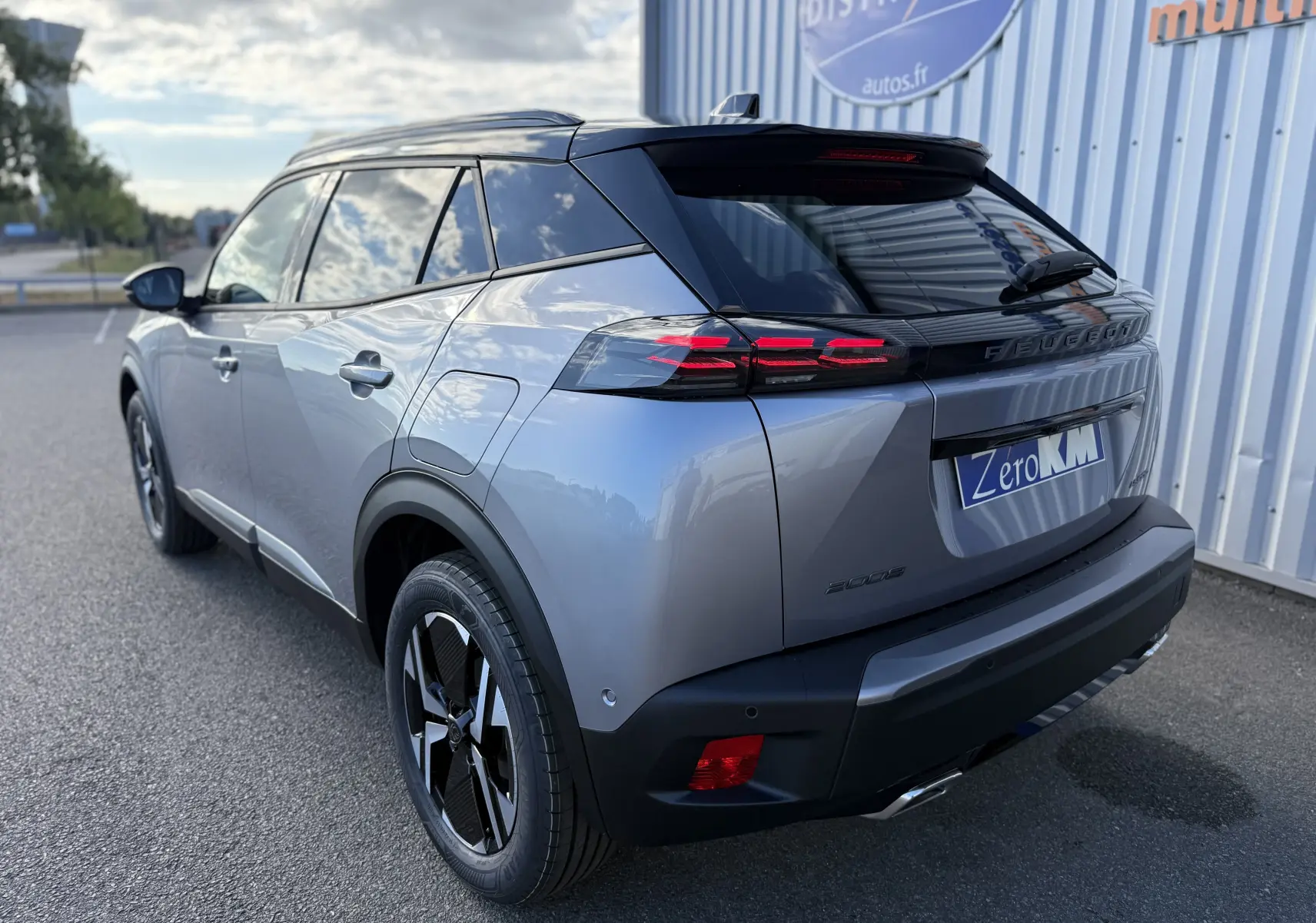 Vue 3/4 arrière droite d’un Peugeot 2008 Hybrid 145 gris Artense avec toit noir et feux arrière LED distinctifs.