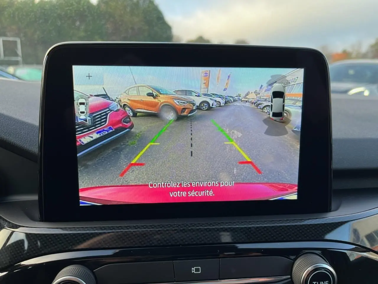 Écran de caméra de recul montrant l'arrière rouge Lucifer du Ford Kuga 1.5 EcoBoost ST-Line en stationnement.