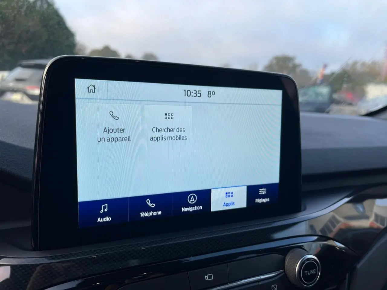 Écran tactile central du Ford Kuga 2022 affichant les options audio, téléphone, navigation et applications, intérieur noir.