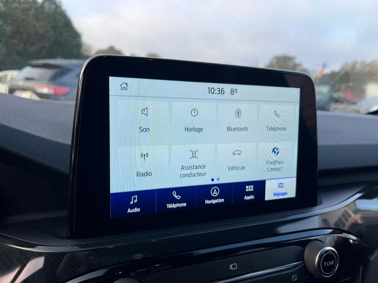 Écran tactile central du Ford Kuga 2022 affichant les options audio, téléphone, navigation et réglages, intérieur moderne.