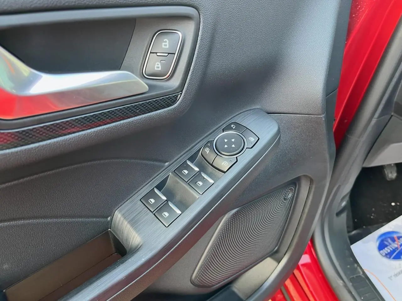 Gros plan sur la porte avant gauche rouge Lucifer du Ford Kuga 2022, montrant les commandes électriques et la poignée intérieure.