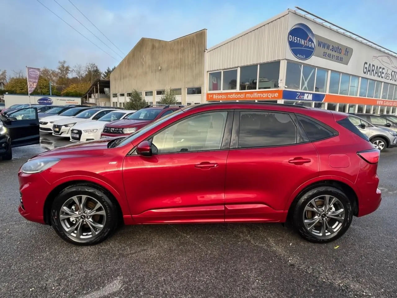 Vue de profil côté gauche d'un Ford Kuga 1.5 EcoBoost 150 ST-Line rouge Lucifer avec vitres surteintées.