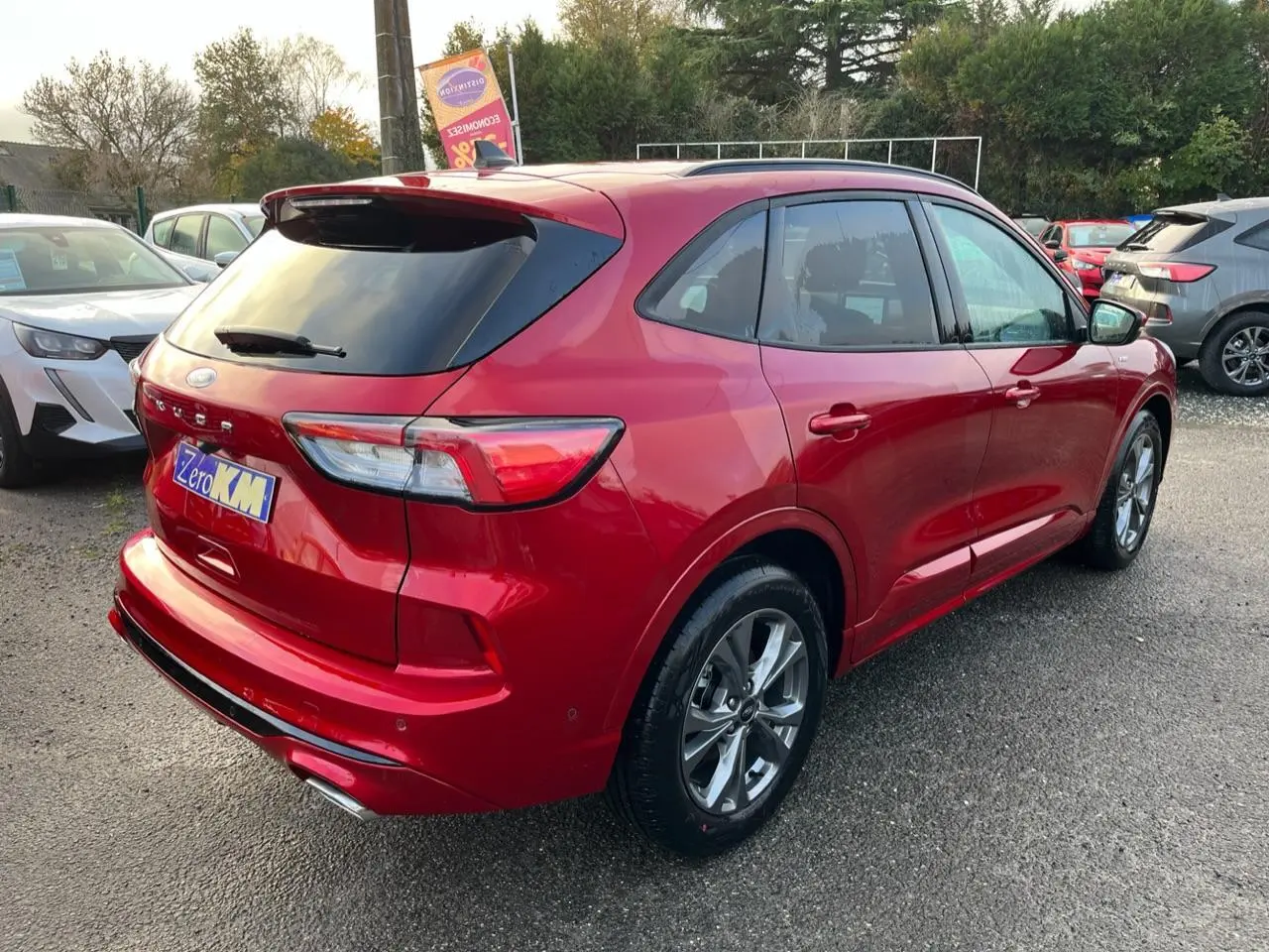 Vue 3/4 arrière droite du Ford Kuga ST-Line rouge Lucifer avec vitres surteintées et double sortie d'échappement.