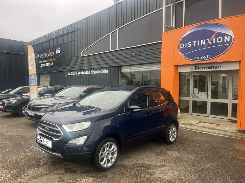 Ford EcoSport 1.0 EcoBoost bleu Abysse vu de 3/4 avant droit devant un concessionnaire avec calandre chromée.