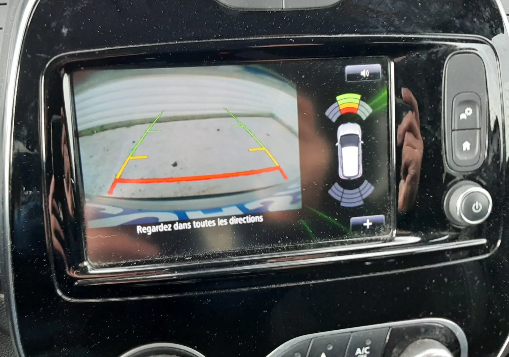 Vue rapprochée de l'écran multimédia du Renault Captur 2017 montrant la caméra de recul avec guidage et capteurs d'aide au stationnement.