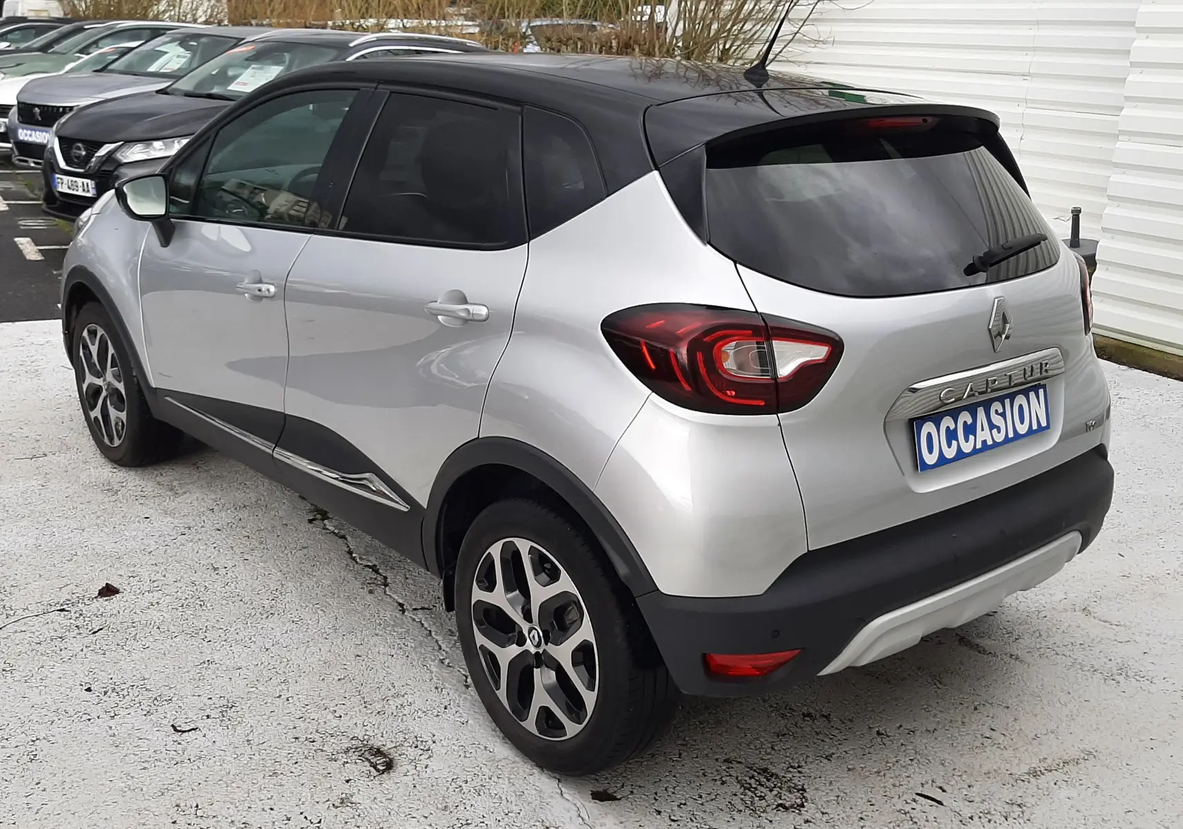 Vue 3/4 arrière droite d'un Renault Captur gris à toit noir avec jantes alliage et vitres teintées.