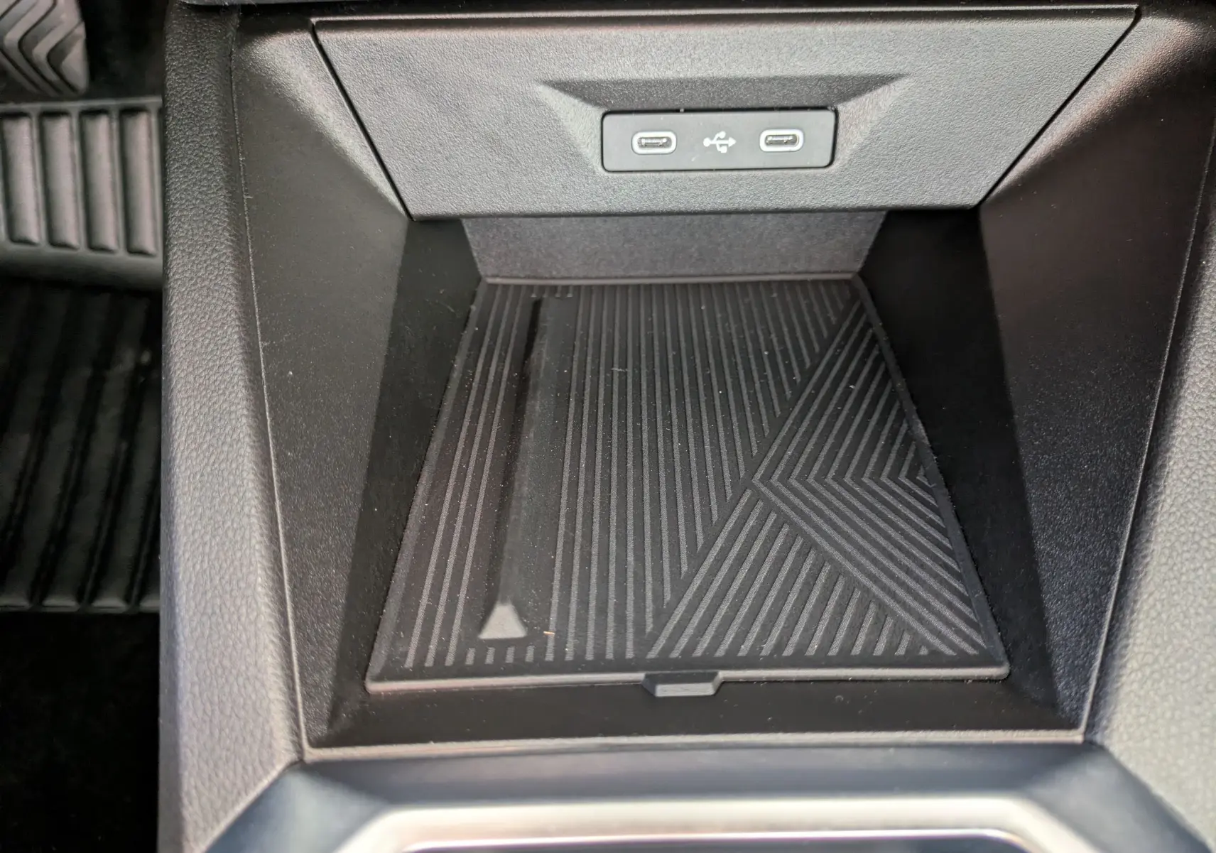 Vue rapprochée de la console centrale noire de la Renault Clio VI TCe 115ch Techno, avec ports USB et surface antidérapante.