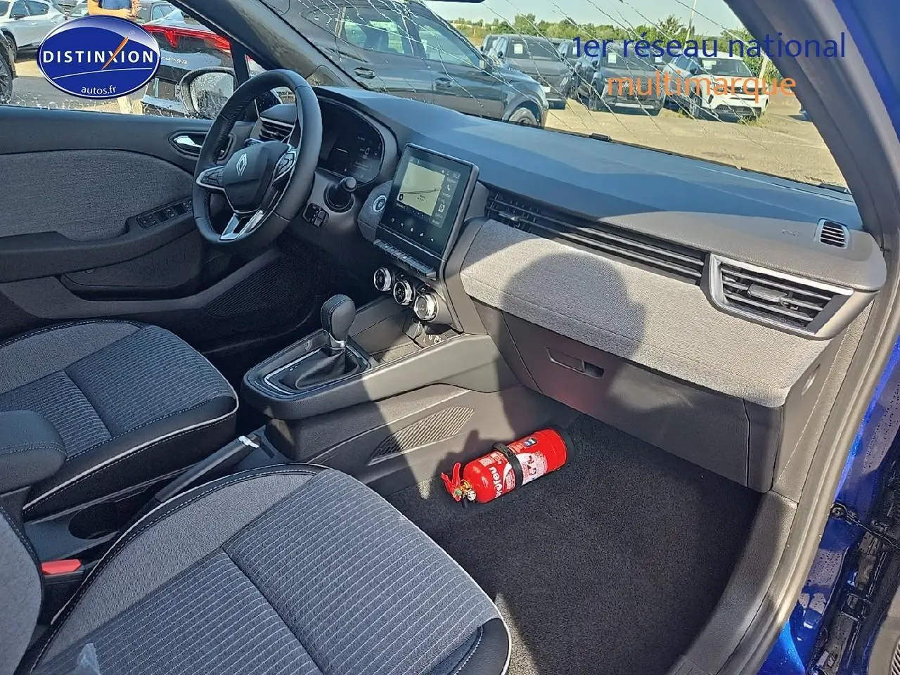 Intérieur avant droit de la Renault Clio V bleu iron, avec tableau de bord moderne et siège tissu gris.