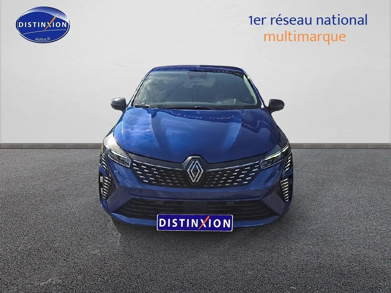 Renault Clio V 1.6 e-tech 145 techno bleu iron vue de face avec calandre chromée et feux LED allumés.