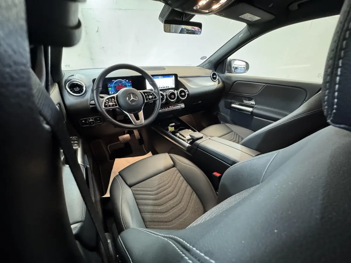 Vue intérieure côté conducteur du Mercedes GLA 250 e Business Line 2023, avec tableau de bord numérique et sièges noirs.