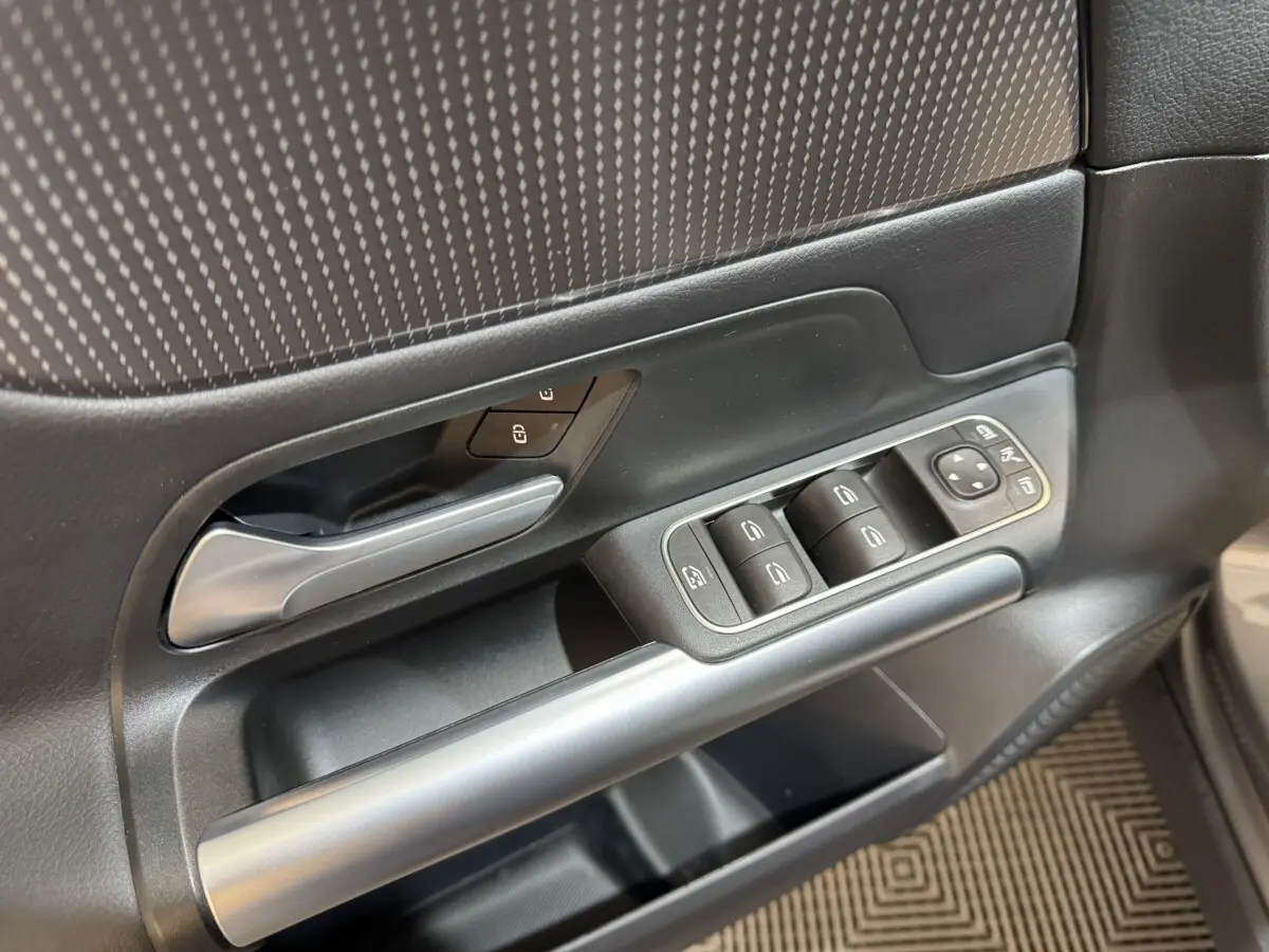 Gros plan sur la porte côté gauche gris foncé du Mercedes GLA 250 e avec commandes des vitres et poignée argentée.