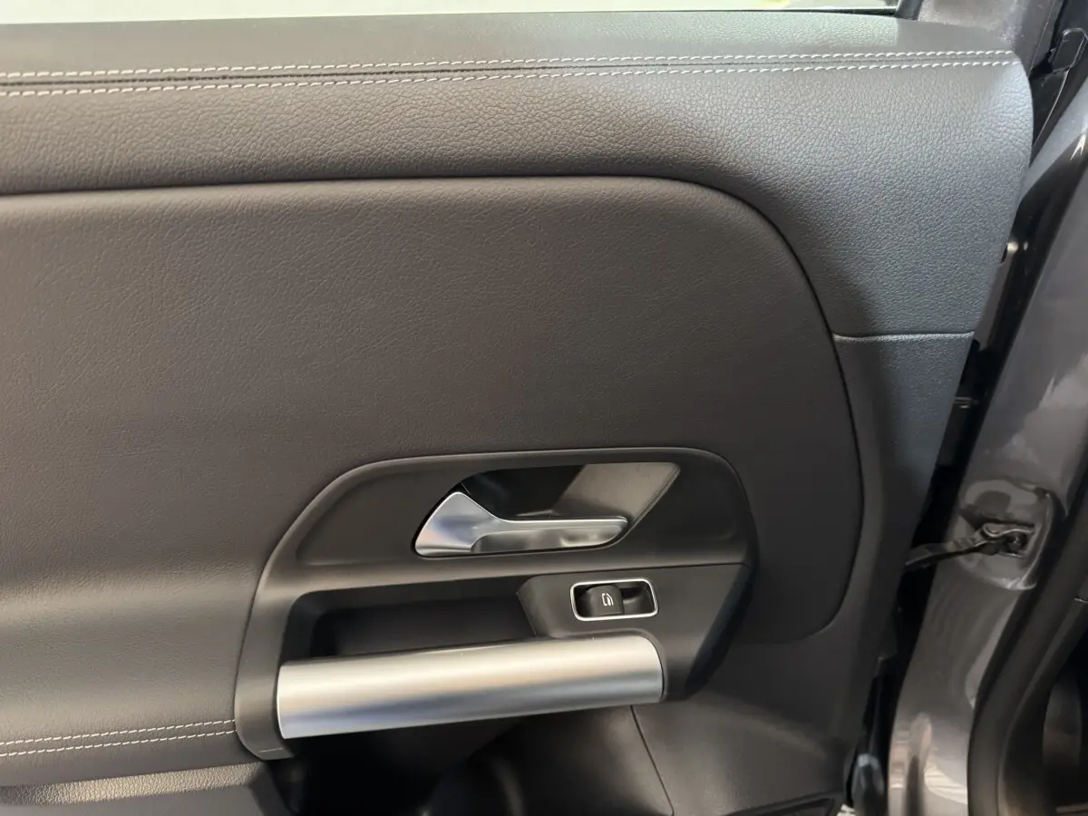 Gros plan sur la porte intérieure côté gauche gris foncé du Mercedes GLA 250 e Business Line 2023 avec poignée alu et bouton de verrouillage.