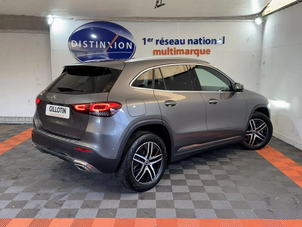 Mercedes GLA 250 e Business Line gris foncé vu en 3/4 arrière droit, feux LED allumés et jantes alliage visibles.