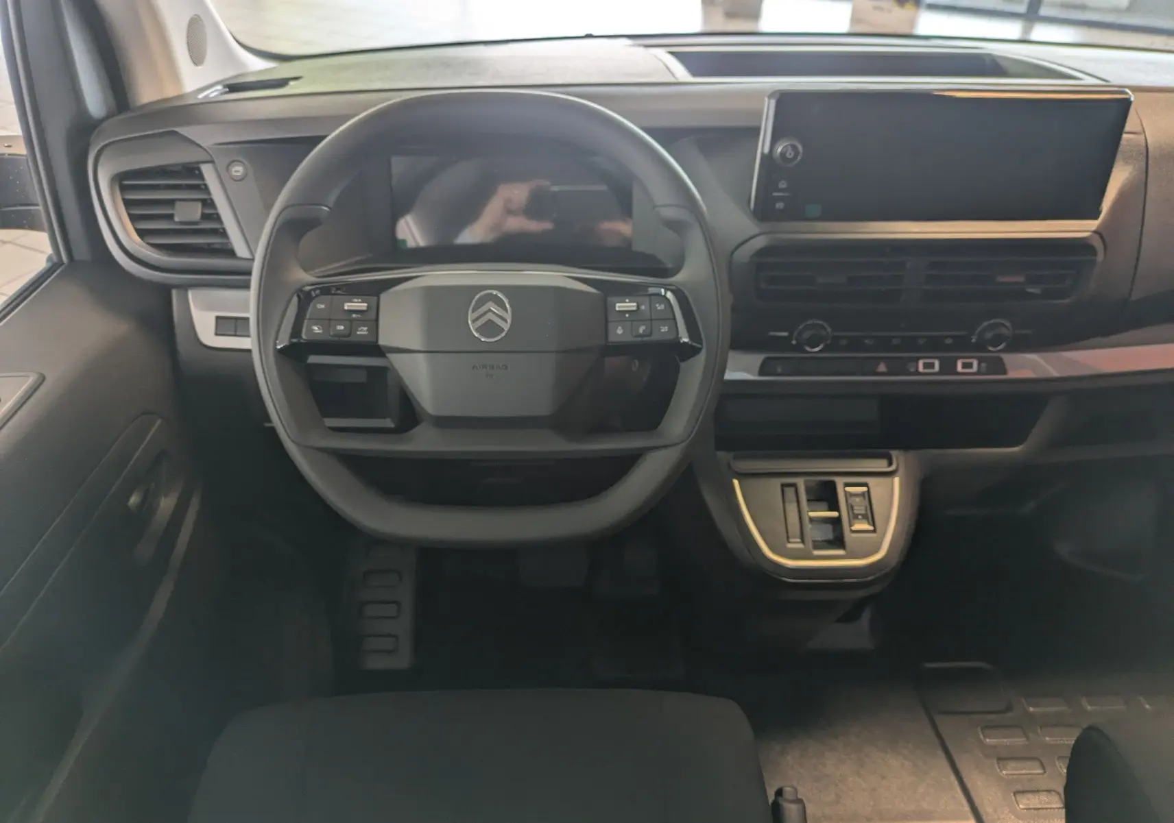 Vue intérieure frontale du poste de conduite noir du Citroën Jumpy Cabine Approfondie avec écran tactile et volant multifonction.